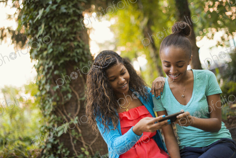 Scenes from urban life in New York City. Two girls looking at a cell phone or computer…