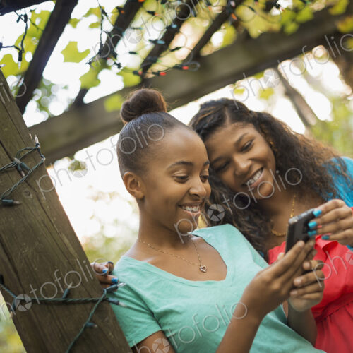 Scenes from urban life in New York City. Two girls looking at a cell phone or computer… Scenes from urban life in New York City. Two girls looking at a cell phone or computer…