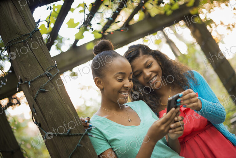 Scenes from urban life in New York City. Two girls looking at a cell phone or computer…