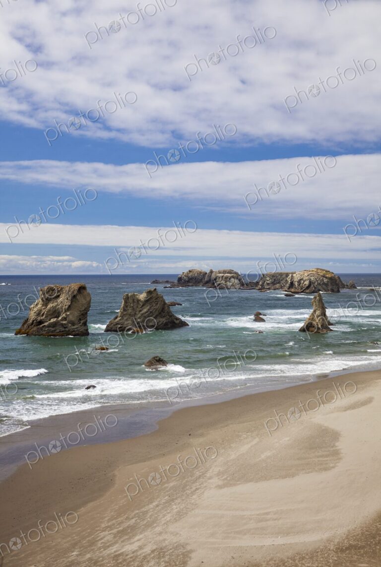 Scenic view of sea stacks rising from the Pacific Ocean along the sandy shoreline of…