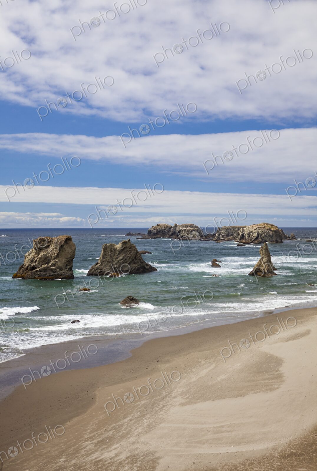Scenic view of sea stacks rising from the Pacific Ocean along the sandy shoreline of…