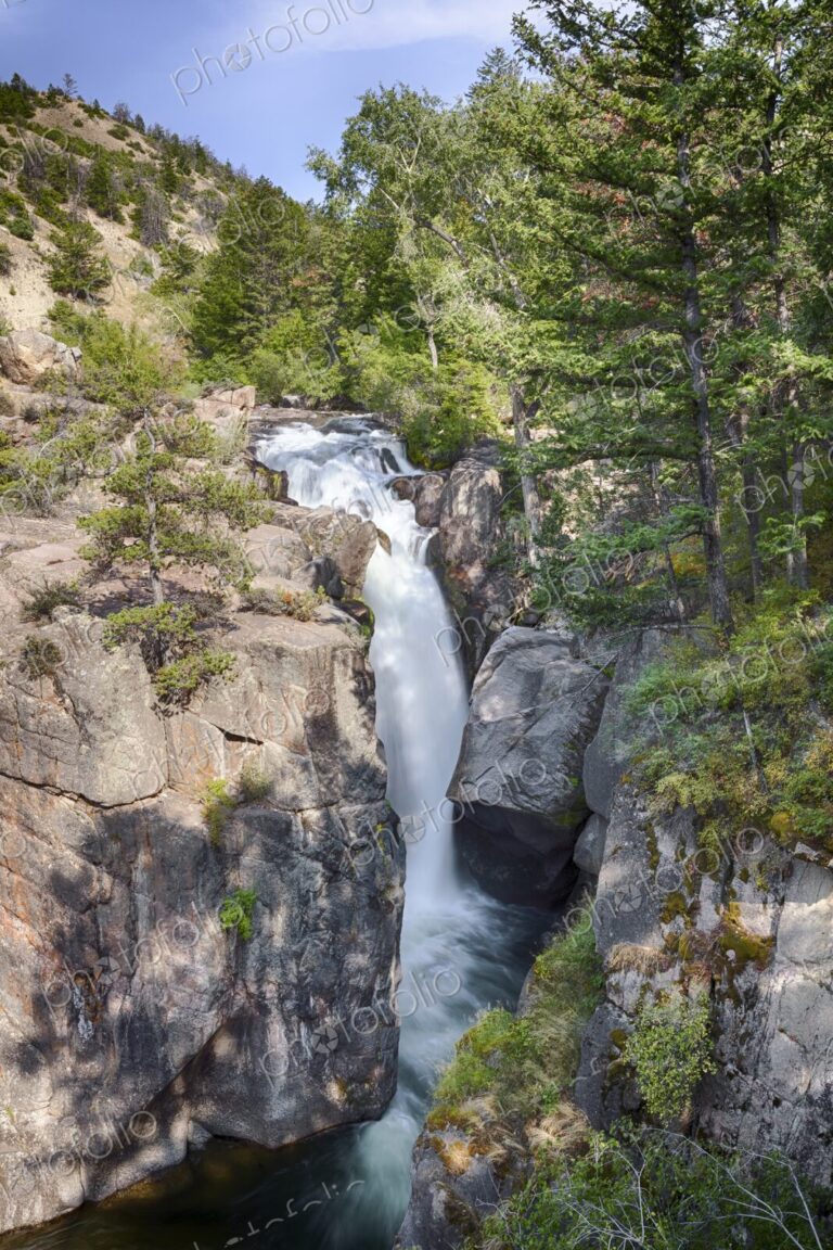 Scenic waterfall cascading through rocky cliffs and lush forest at Shell Falls in…