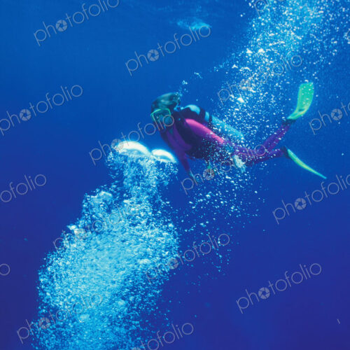Scuba diver swims through a stream of bubbles.