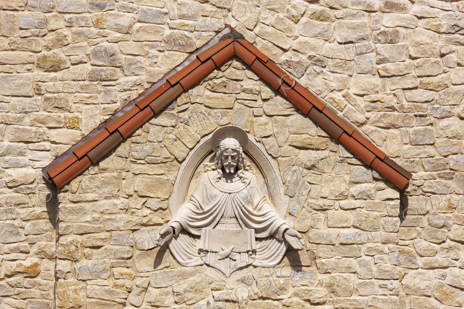 Sculpture of Jesus set into stone wall.