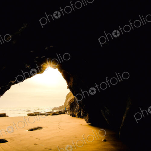 Sea cave, view from a rock cave out to the beach and the shoreline.
