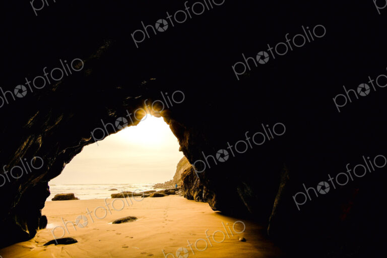 Sea cave, view from a rock cave out to the beach and the shoreline.