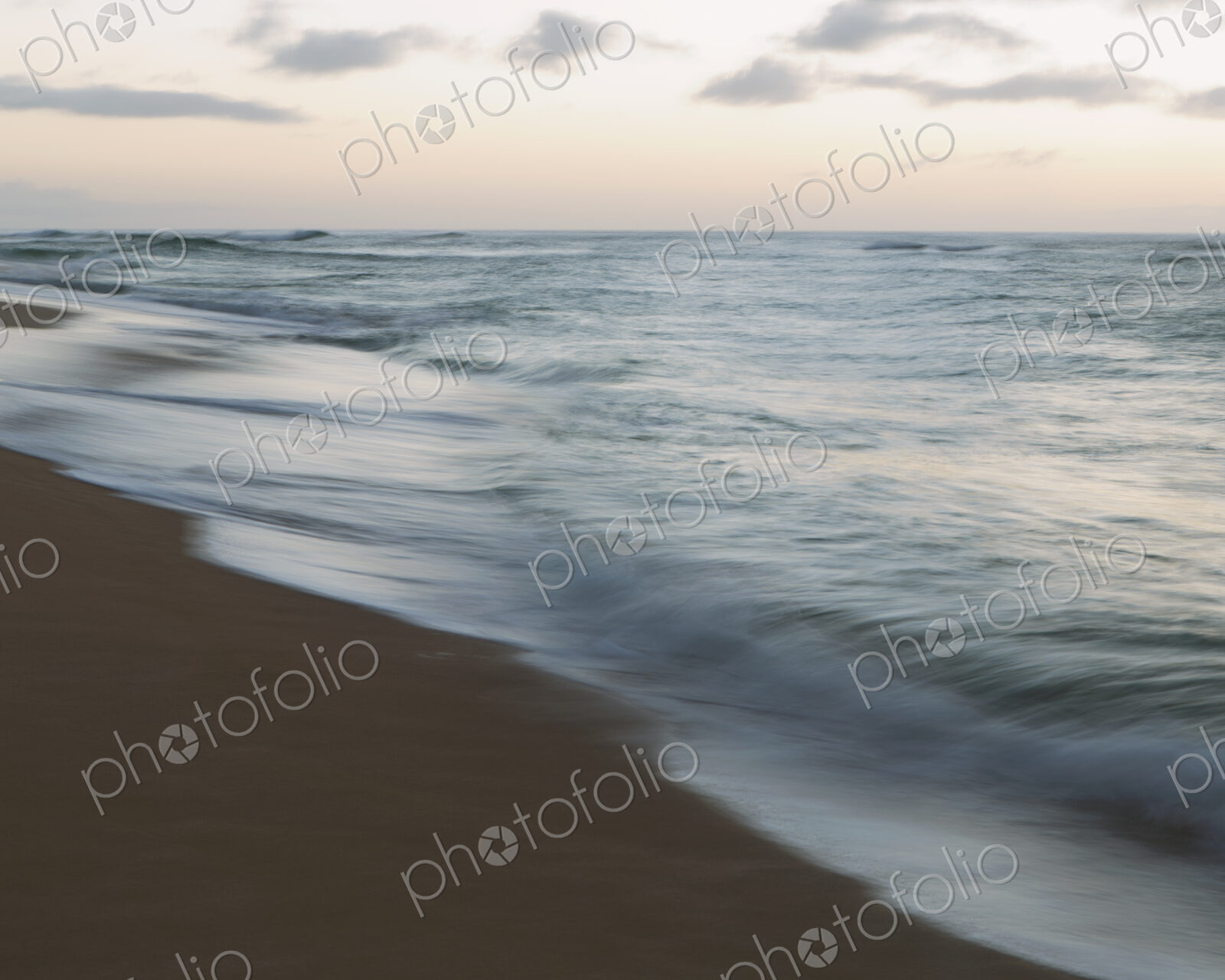 Seascape and crashing waves on beach at dusk.