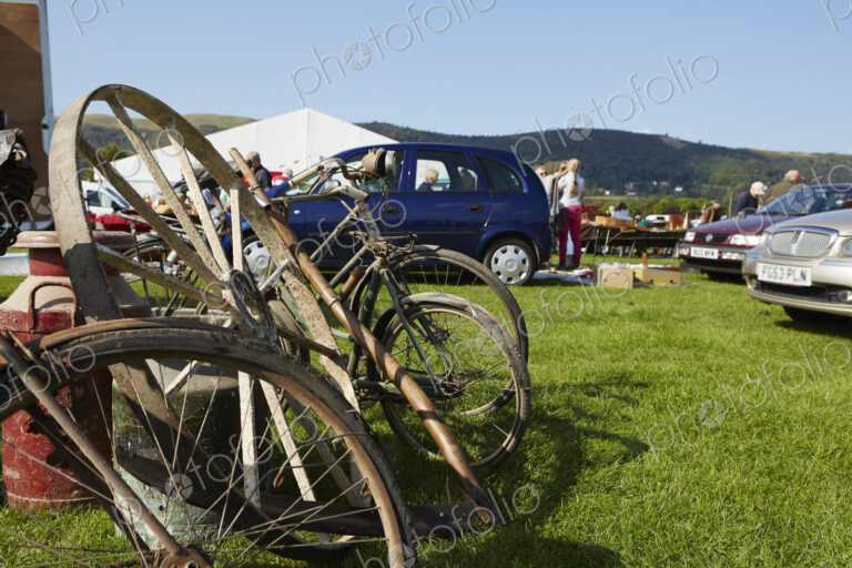 Selection of vintage bicycles, wheel rim and an old milk churn for sale at a flea…
