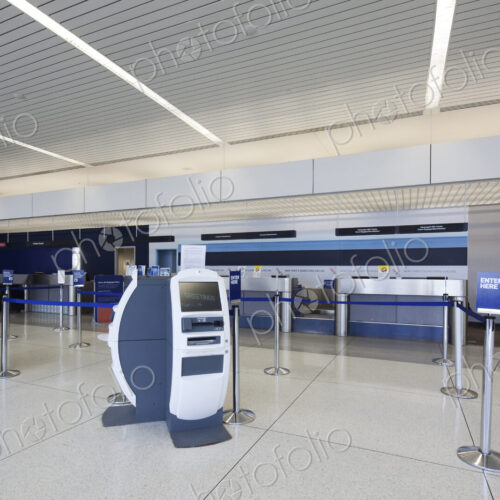 Self check-in desks and traditional baggage check in desks in an empty airport.