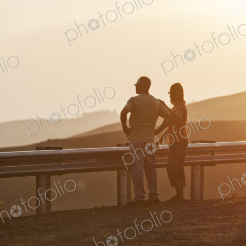 Senior couple watching a sunset from a rest stop on a road trip in eastern Washington…