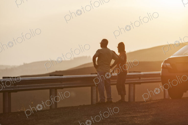 Senior couple watching a sunset from a rest stop on a road trip in eastern Washington…