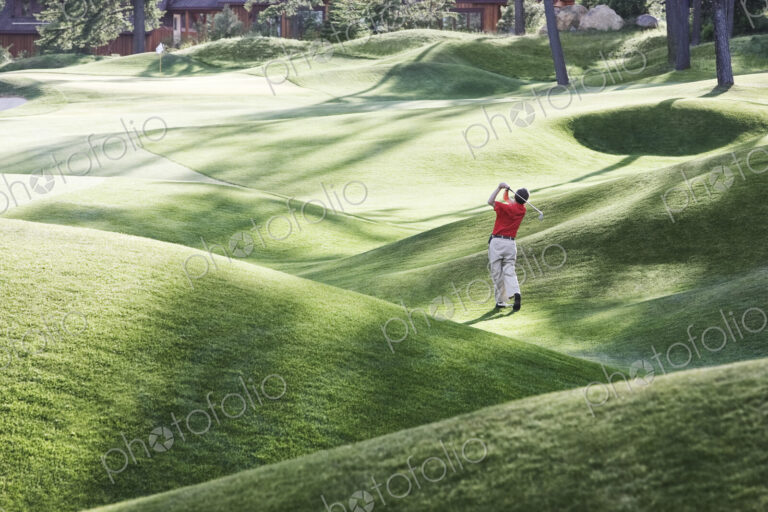 Senior golfer hitting a second shot from the fairway of a golf course.