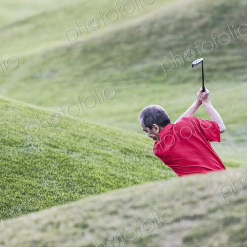 Senior golfer hitting a second shot from the fairway of a golf course. Senior golfer hitting a second shot from the fairway of a golf course.