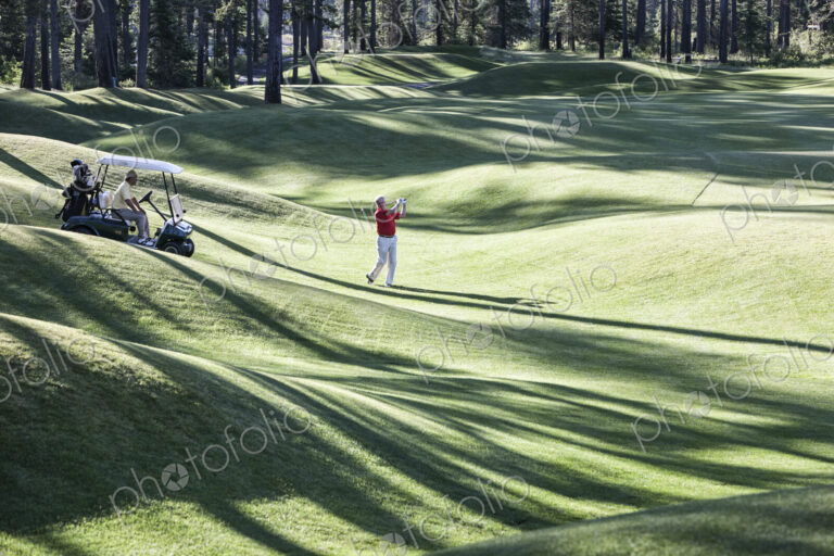 Senior golfer hitting a second shot from the fairway of a golf course.