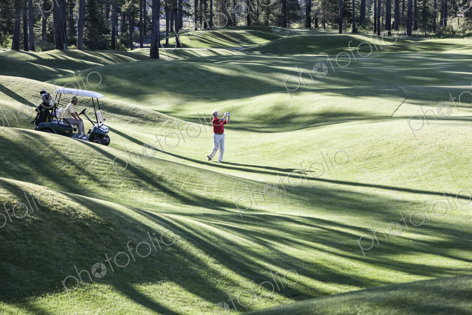 Senior golfer hitting a second shot from the fairway of a golf course.