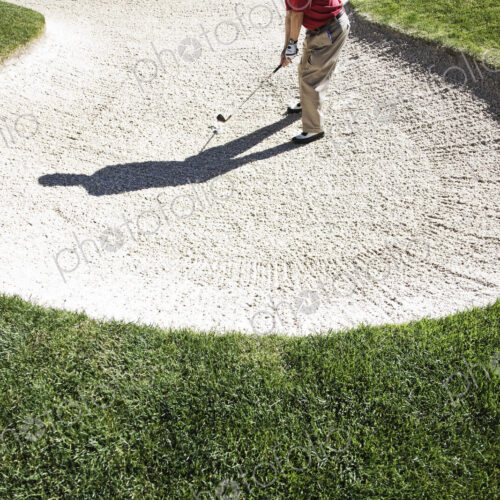 Senior golfer playing out of a bunker on the golf course. Senior golfer playing out of a bunker on the golf course.