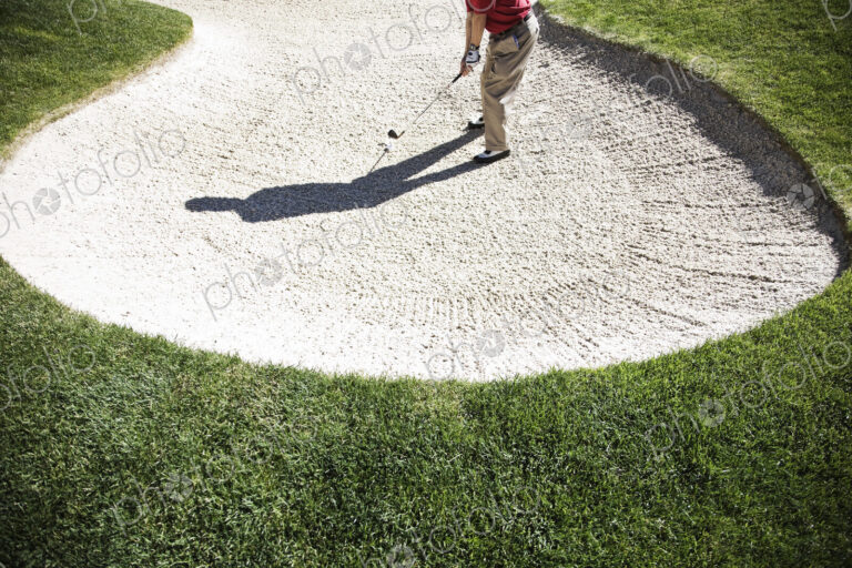 Senior golfer playing out of a bunker on the golf course.