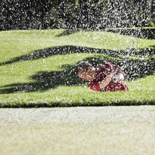 Senior golfer playing out of a bunker on the golf course. Senior golfer playing out of a bunker on the golf course.