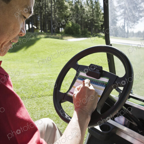 Senior golfer recording his score on a score card in a golf cart. Senior golfer recording his score on a score card in a golf cart.