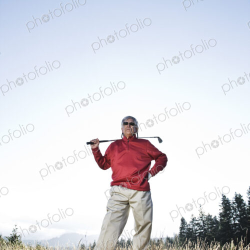 Senior golfer standing in heavy rough pondering his next shot.