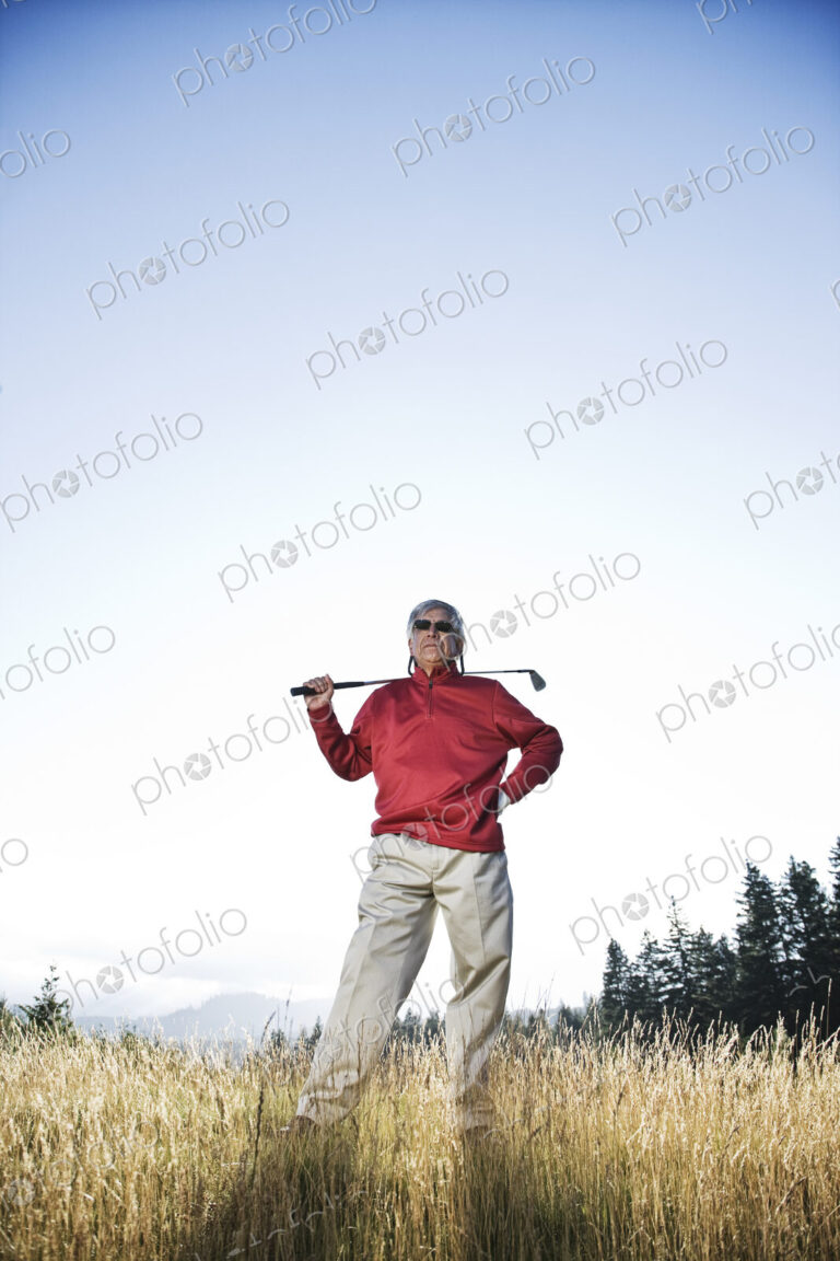 Senior golfer standing in heavy rough pondering his next shot.
