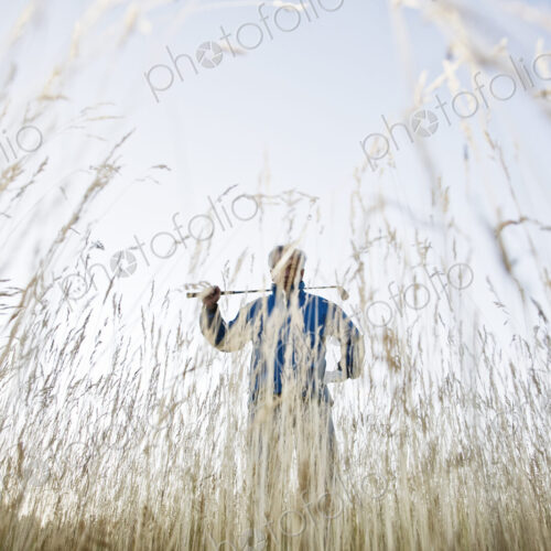 Senior golfer standing in heavy rough pondering his next shot.