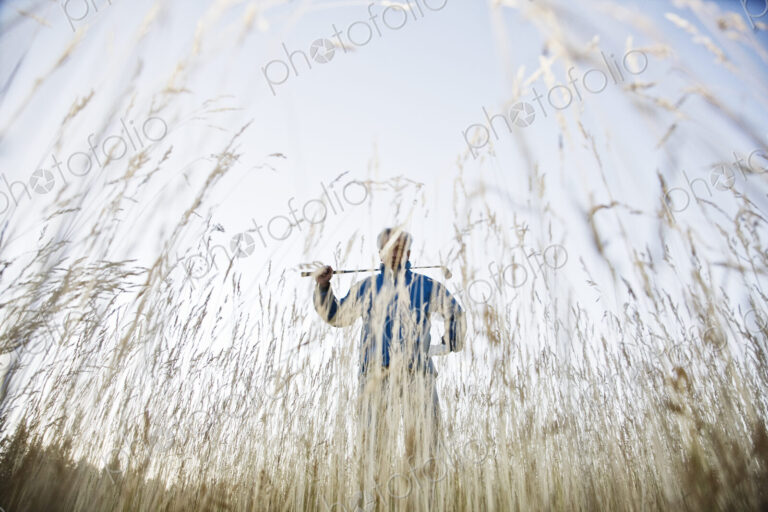 Senior golfer standing in heavy rough pondering his next shot.