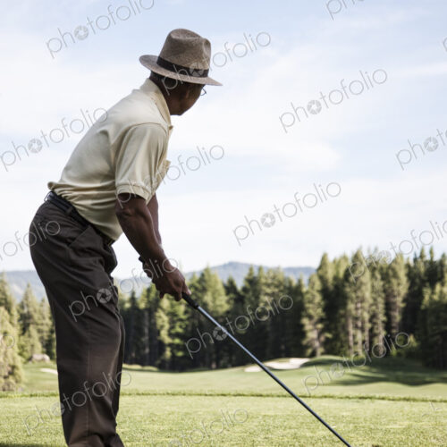 Senior golfer teeing off during a round of golf. Senior golfer teeing off during a round of golf.