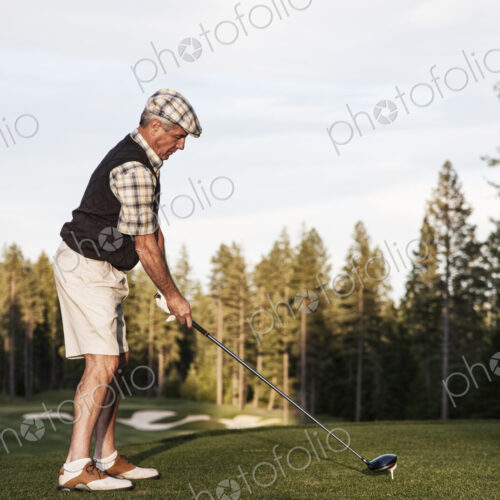 Senior golfer teeing off during a round of golf. Senior golfer teeing off during a round of golf.