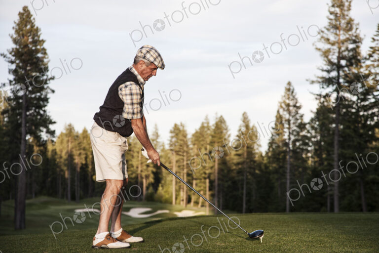 Senior golfer teeing off during a round of golf.