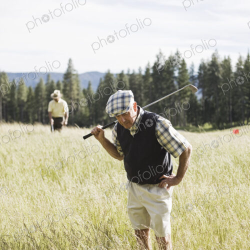 Senior golfer trying to find golf ball that has flown into heavy rough on the golf course. Senior golfer trying to find golf ball that has flown into heavy rough on the golf course.