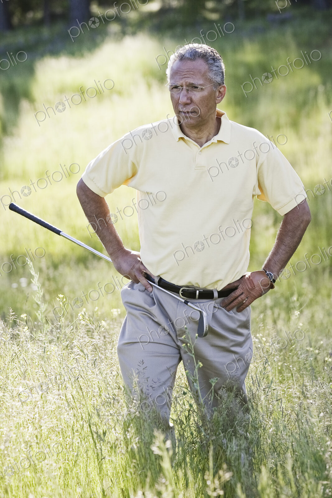 Senior golfer trying to find golf ball that has flown into heavy rough on the golf course.