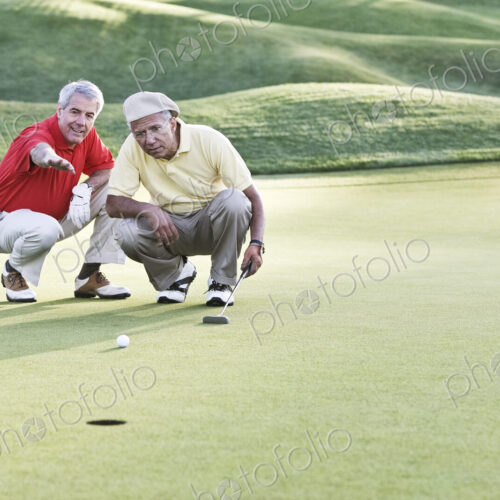 Senior golfers judging the lie on one of the greens of the golf course. Senior golfers judging the lie on one of the greens of the golf course.