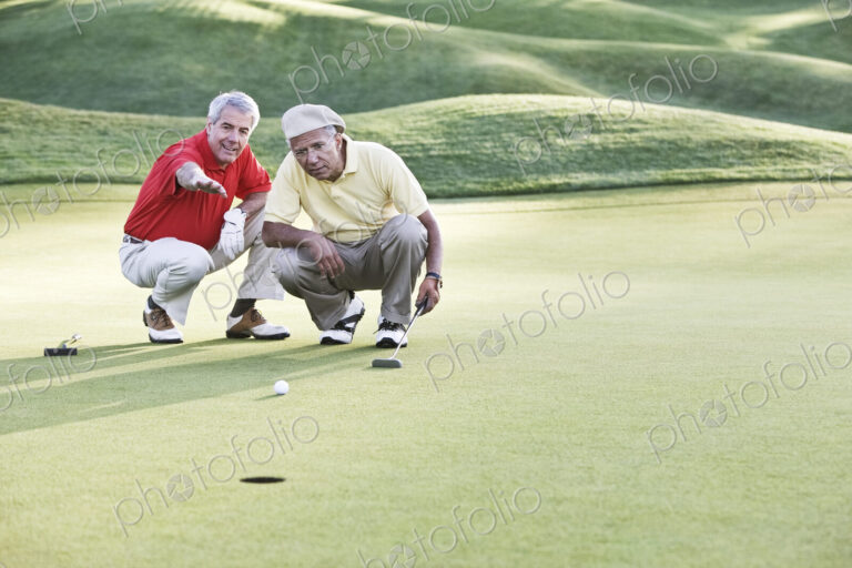 Senior golfers judging the lie on one of the greens of the golf course.