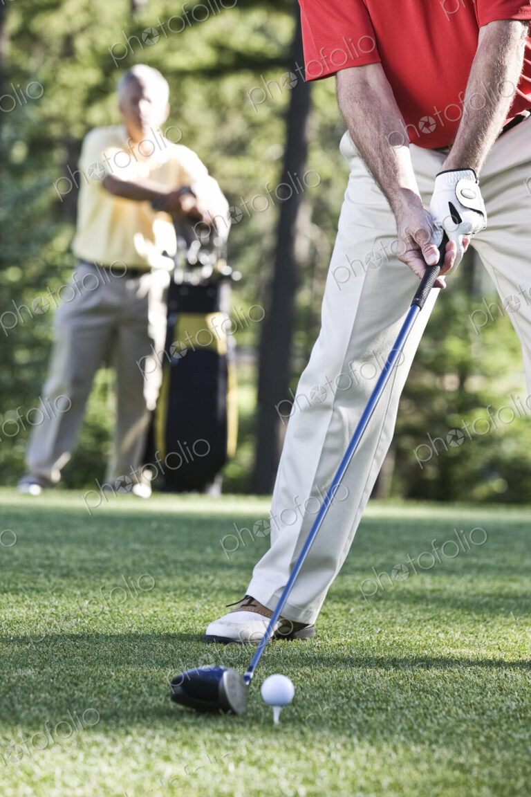 Senior golfers teeing off on a golf course hole.