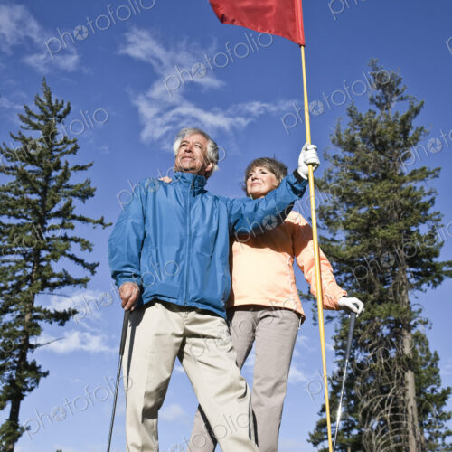 Senior golfing couple on a green with the flag.