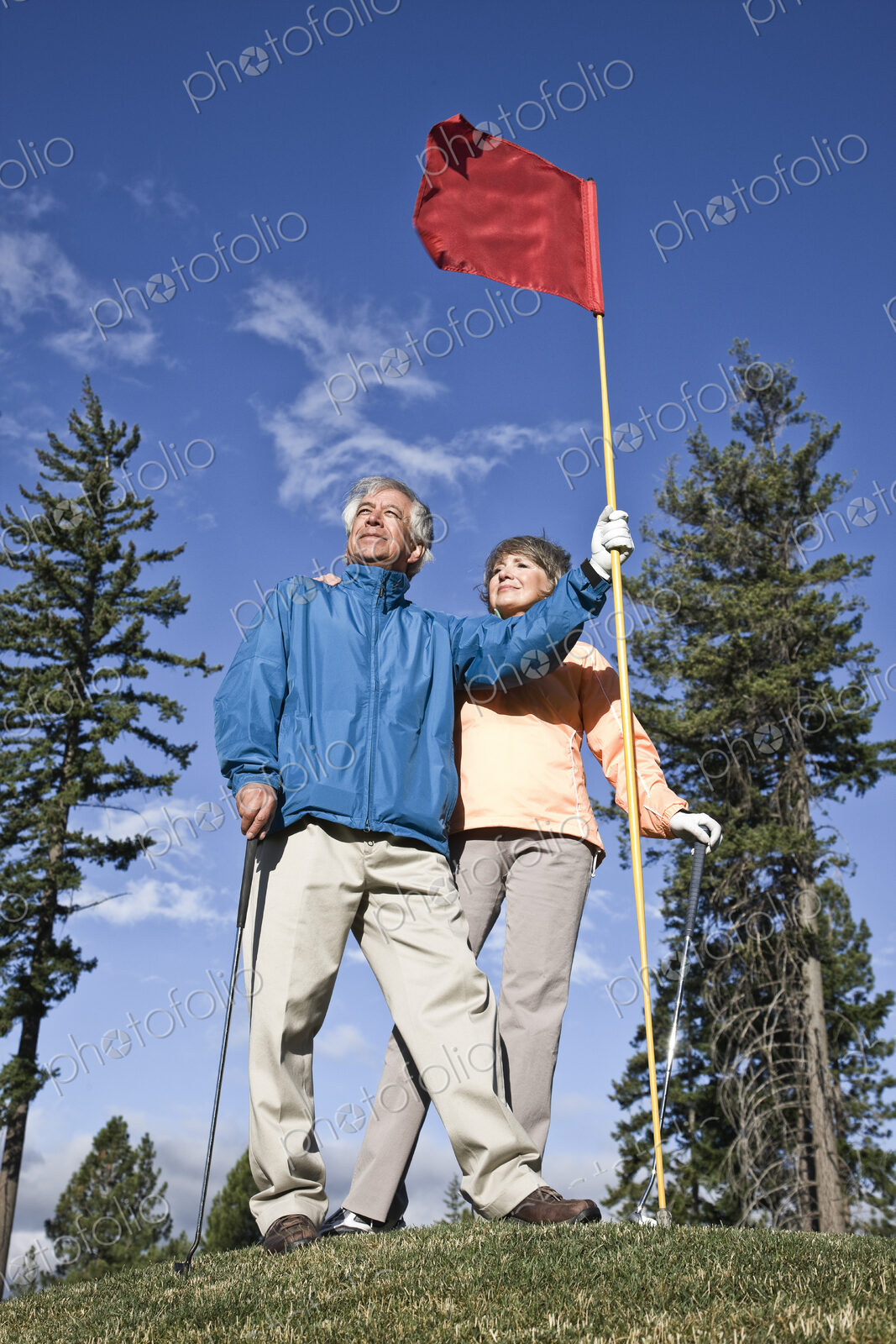 Senior golfing couple on a green with the flag.