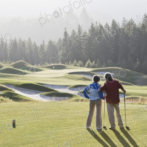Senior golfing couple surveying the next tee shot toward the green.