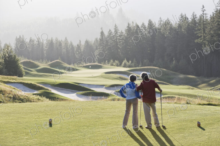 Senior golfing couple surveying the next tee shot toward the green.