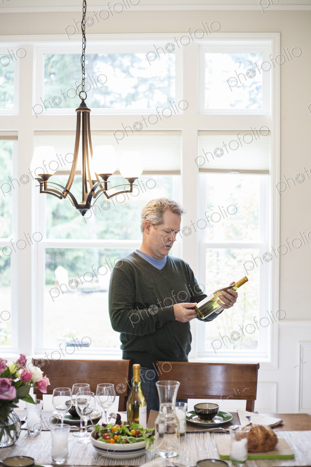 Senior man checking a bottle of wine prior to a home dinner party.