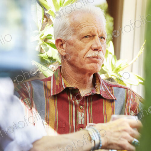 Senior man with moustache sitting outdoors.