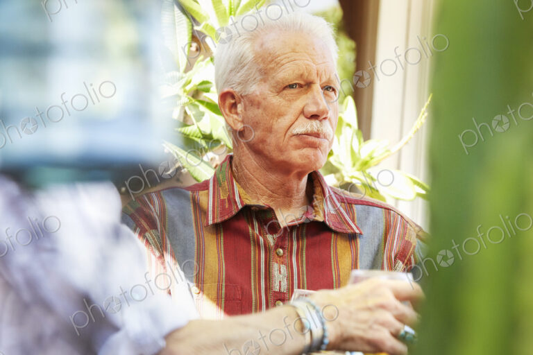 Senior man with moustache sitting outdoors.