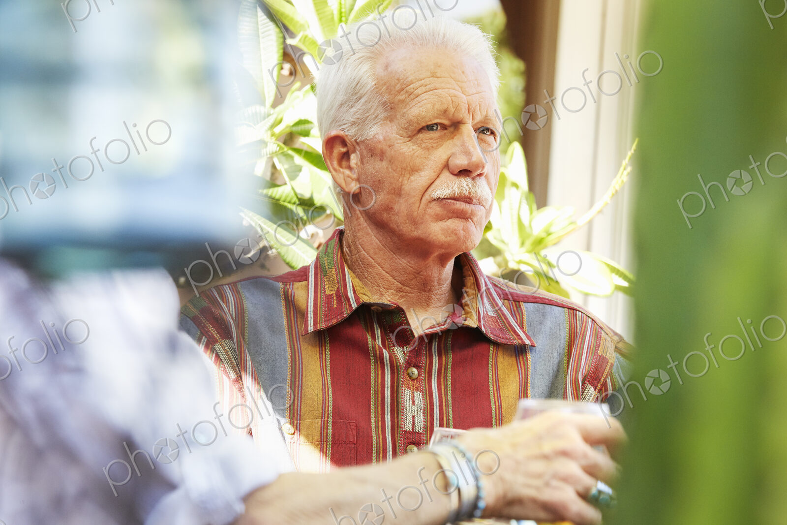 Senior man with moustache sitting outdoors.