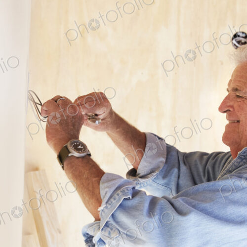 Senior man working on electrical wiring in a house.