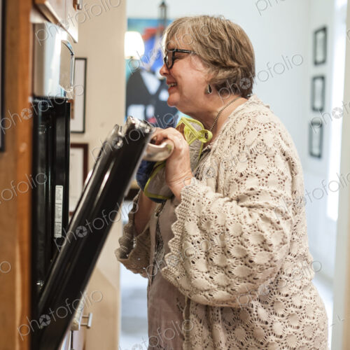 Senior woman checking in the oven to see if a dish is finished cooking.