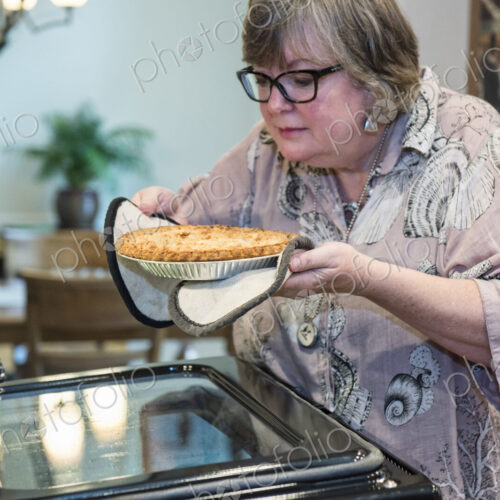 Senior woman checking to a see if a home cooked pie is ready to come out of the oven.