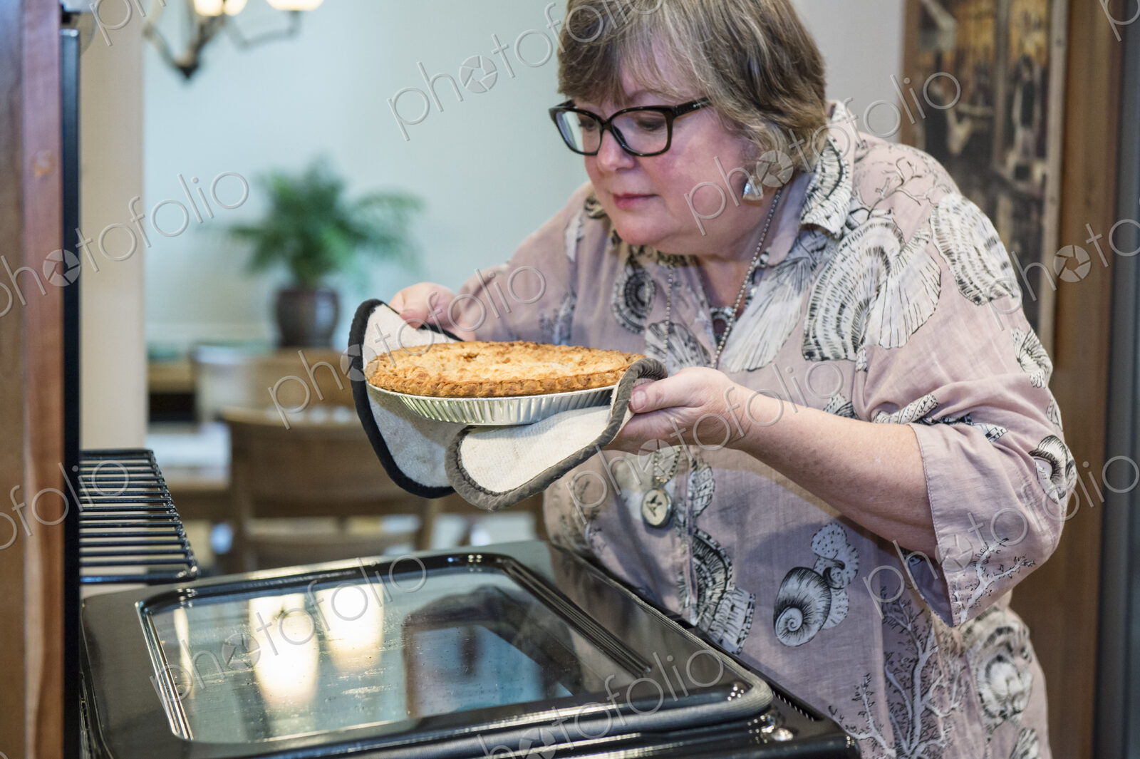 Senior woman checking to a see if a home cooked pie is ready to come out of the oven.