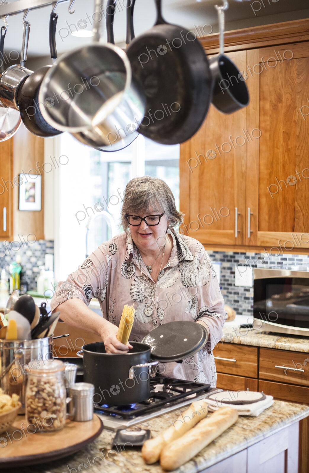 Senior woman checking to see if a pot of pasta is cooking correctly in a home kitchen.