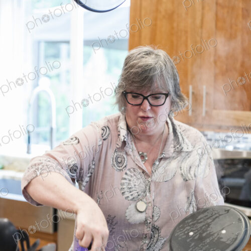 Senior woman checking to see if a pot of pasta is cooking correctly in a home kitchen.