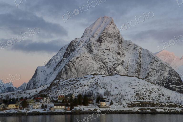 Settlement on a shore, with snow-capped mountains behind.